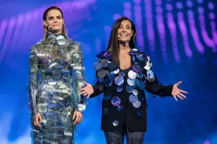 Lijepa žena na sceni u svjetlucavoj haljini od krupnih diskova, pozadina plavog svjetla.