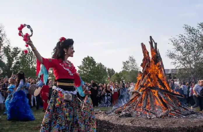 Vesela žena u tradicionalnoj nošnji pleše pored velike vatre na kulturnom festivalu u Krušnici.