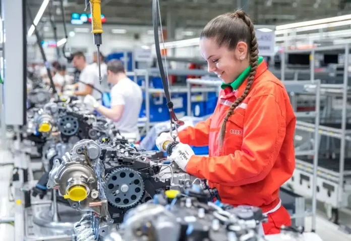 Motivisana žena u tvornici automobila sastavlja motore, fokus na preciznost i kvalitet.