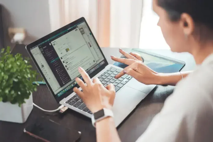 Učesnica koristi laptop za rad ili komunikaciju, fokusirana na ekran, u uredskom okruženju.