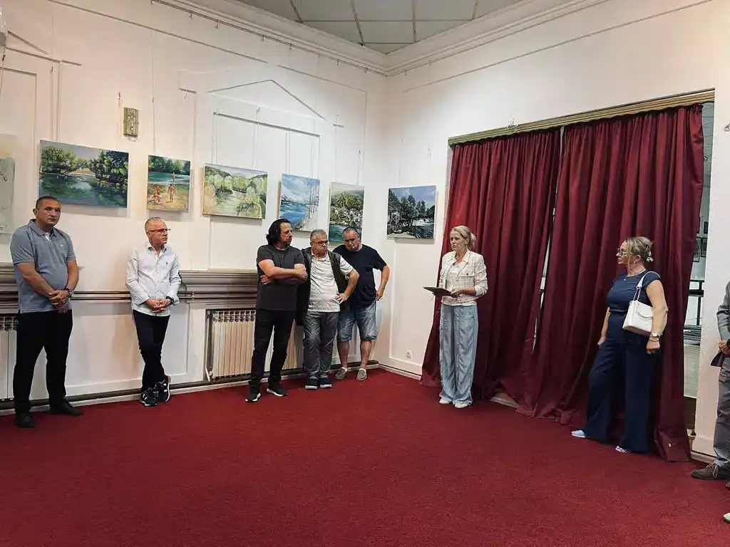 Umjetnički izložba u galeriji Krušnica sa posjetiocima i slikama prirode na zidovima.