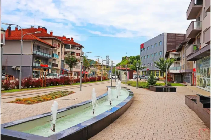 Sunčana ulica u Krušnici s fontanama i modernom arhitekturom.