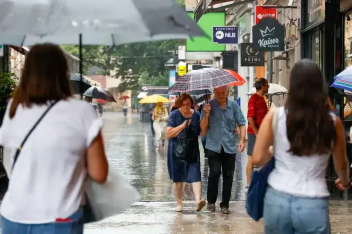 Kišobran u kišnom danu na ulici, ljudi šetaju tokom kišnog vremena, pješačka zona u gradu, aktivnosti na otvorenom tokom kiše.