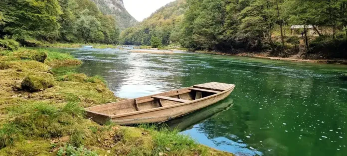 Mirna rijeka Krušnica u prirodi sa drvenom čamcem na obali, Bosna i Hercegovina.