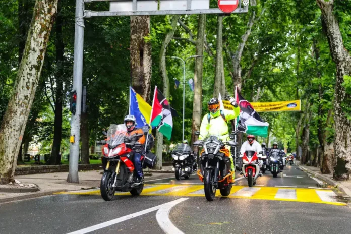 Vožnja motocikala kroz drvećenu ulicu, podrška Palestini, zastave, borilački duh, moto skup.