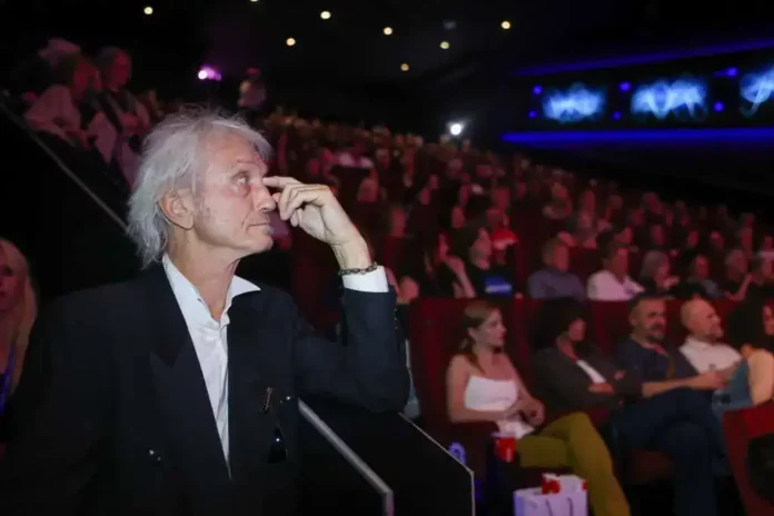 Staro muškarac na koncertu ili događaju u auditorijumu, koncentriran i zadubljen.