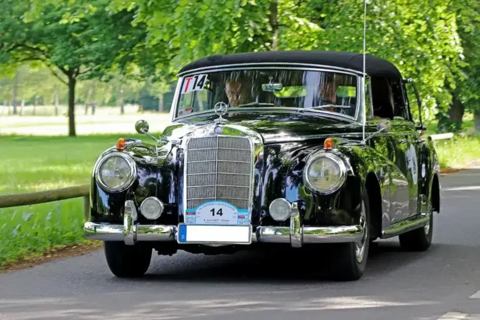 Klasičan crni vintage Mercedes-Benz automobil na ulici u prirodi.