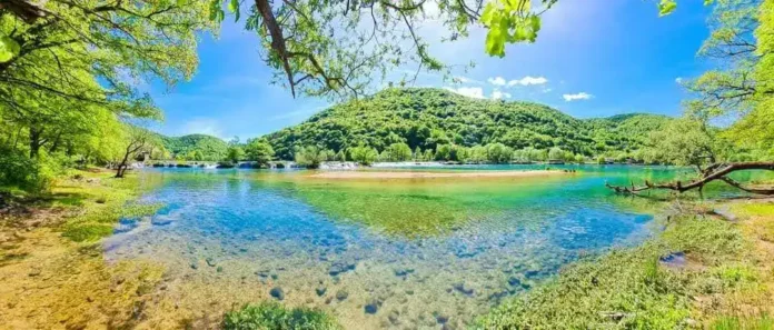 Krušnica rijeka u prirodi, čista i mirna, okružena zelenilom i visokim brdima.
