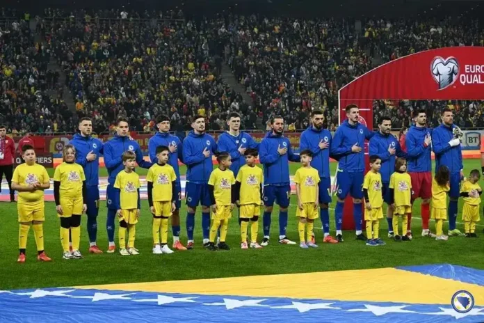 M lijepa fotografija fudbalske reprezentacije pred utakmicu na stadionu, uz djecu i navijače u pozadini.