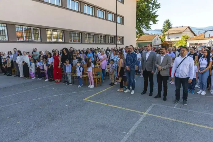 Skupina ljudi na školskom događaju pred školom u Krušnici, dječja i odrastala okupljanja.