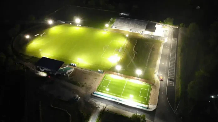 Noćni snimak osvijetljenog nogometnog stadiona Krušnica, sportski teren i tribine.