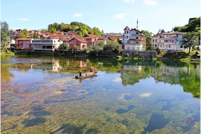 Mirna rijeka Krušnica sa slikovitim selom u pozadini, idealno za odmor i prirodu.