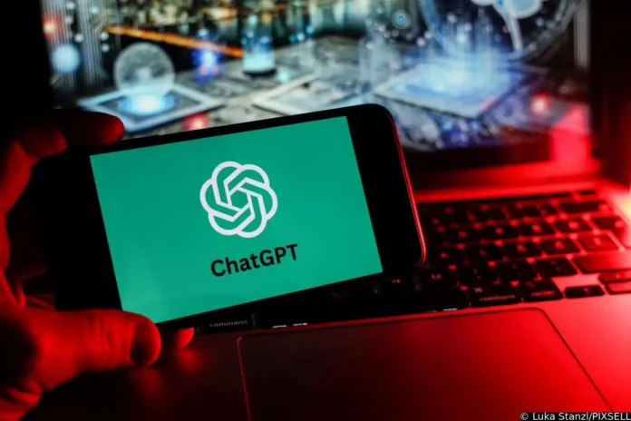 ChatGPT logo na mobilnom telefonu, sjajna digitalna tehnologija, crvena i plava rasvjeta u pozadini.