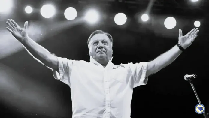 1. Poznati muškarac na sceni s raširenim rukama pod svjetlima pozornice.