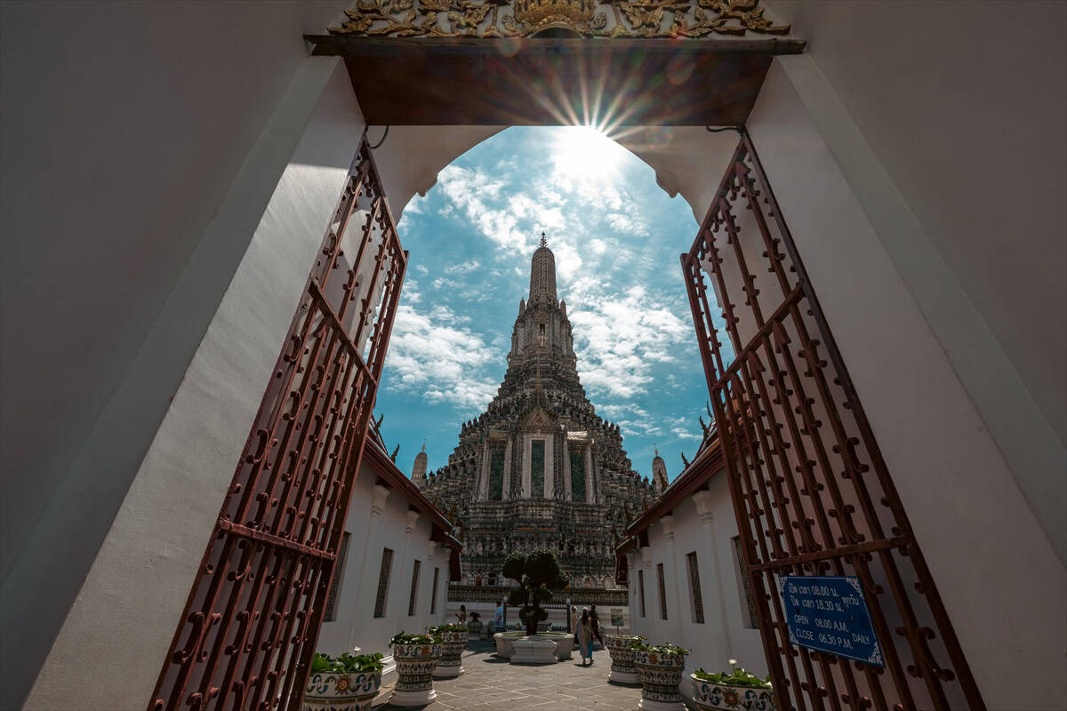 Visoka pagoda Wat Arun u Bangkoku, Tajland, pod suncem i oblacima.