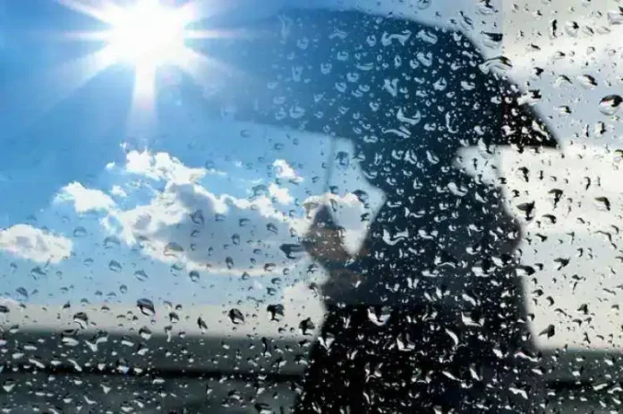 Ostaci kiše na prozoru sa vedrim nebom i suncem u pozadini.