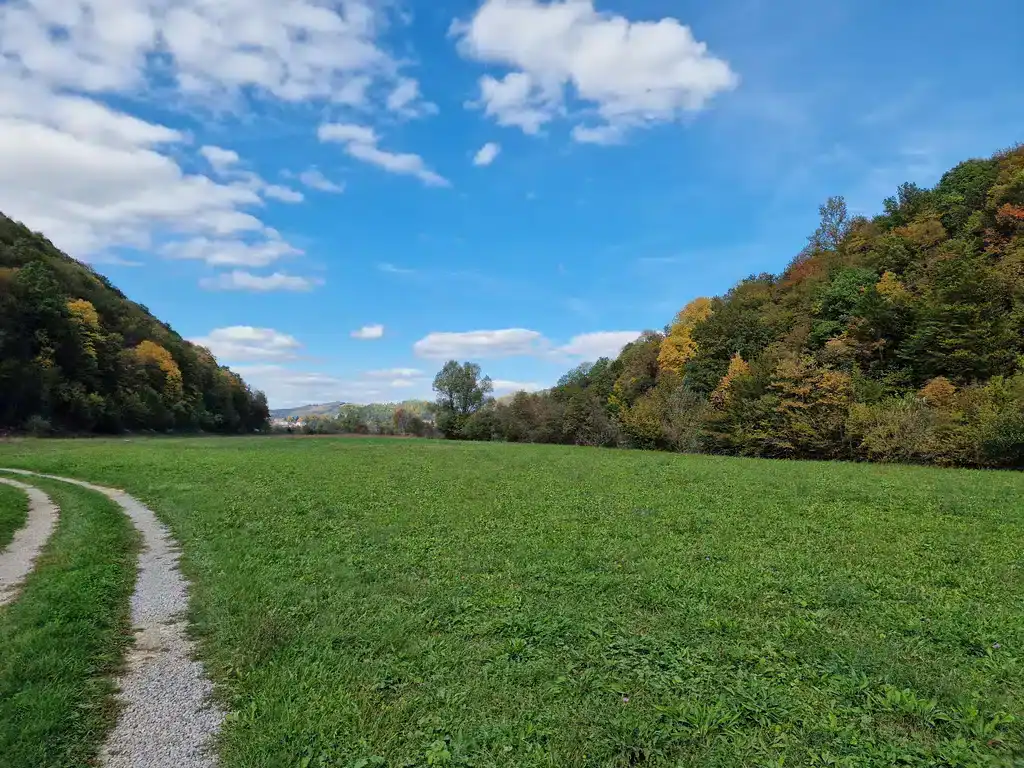 Šumoviti brežuljci i zelena polja u dolini Krušnice, idilični pejzaž u prirodi.