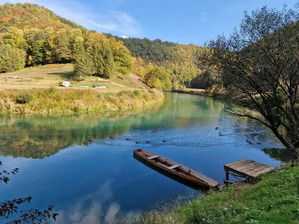 Mirno jezero Krušnica okruženo šumama i brdima u jesenjem razdoblju.