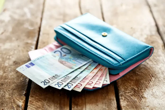 Plavi novčanik s evrima na drvenoj površini.