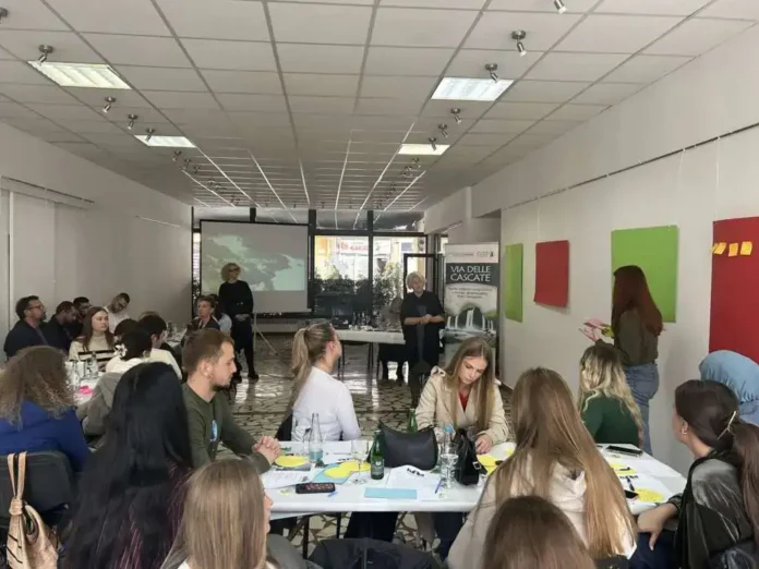 Učiti u prostoriji za sastanke sa grupom ljudi, prezentacija i radni materijali na stolu.