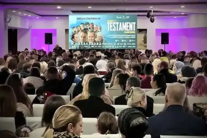 Posjetitelji na konferenciji ili događaju u konferencijskoj sali, fokusirani na prezentaciju.