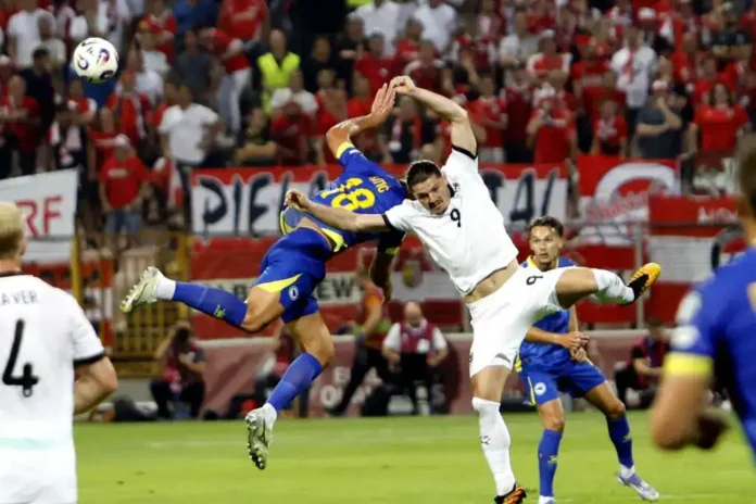 Dinamična utakmica na stadionu Krušnica uz nadmetanje nogometaša u akcionom skoku.