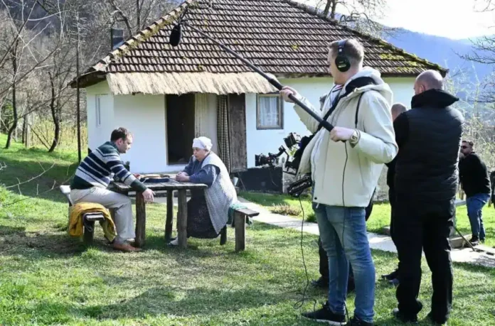 Osmotrna scena snimljena u dvorištu starije kuće u prirodi, s ekipom filmske ekipe na setu.