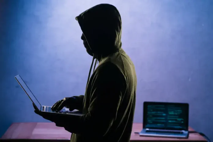 Zlonamjerna osoba s kapuljačom koristi laptop za hakiranje.