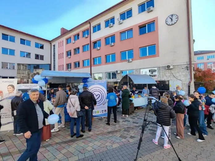 Tročlana grupa ljudi na događaju ispred zgrade u gradu u Bosni i Hercegovini.