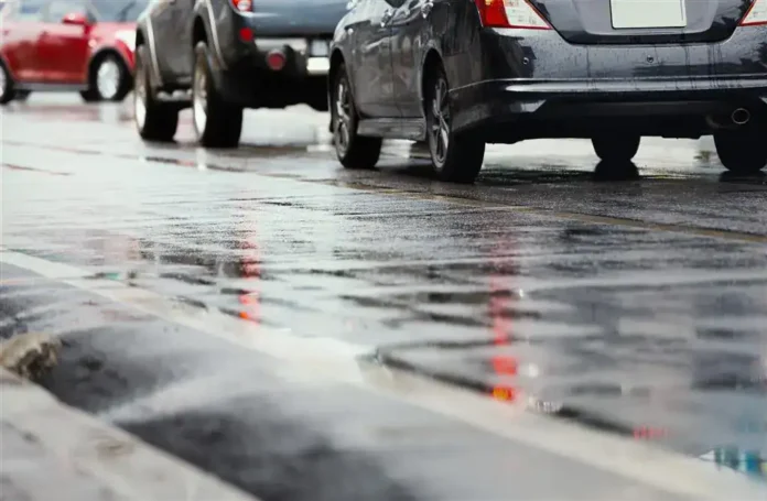 Voda na pločniku nakon kiše, odraz automobila, mokra ulica, prometni saobraćaj, kišna scena, asfalti u vodi, refleksije na površini, gradski promet.