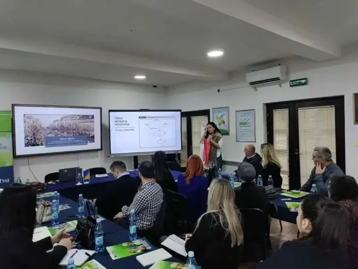 Učesnici konferencije u sali sa prezentacijama i monitorima.