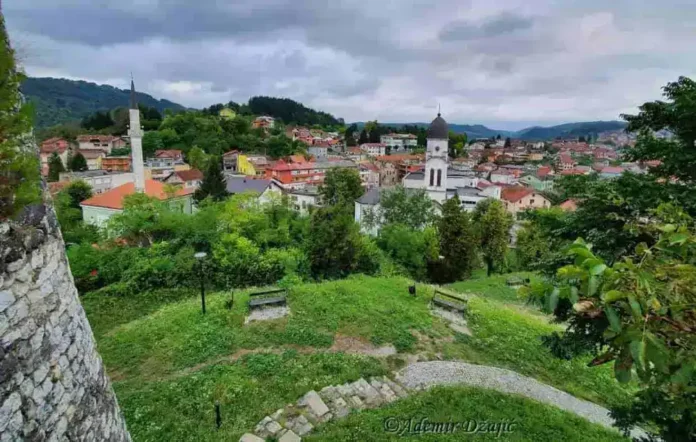 Krušnica Bosna, panorama grada i pejzaža sa zelenim brdima i istorijskim građevinama.