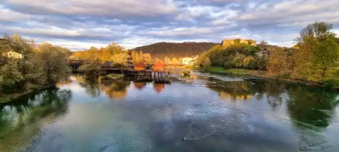 Krušnica rijeka sagrađena u prirodnom okruženju, jesenji pejzaž s mostovima i dvorcima u pozadini.