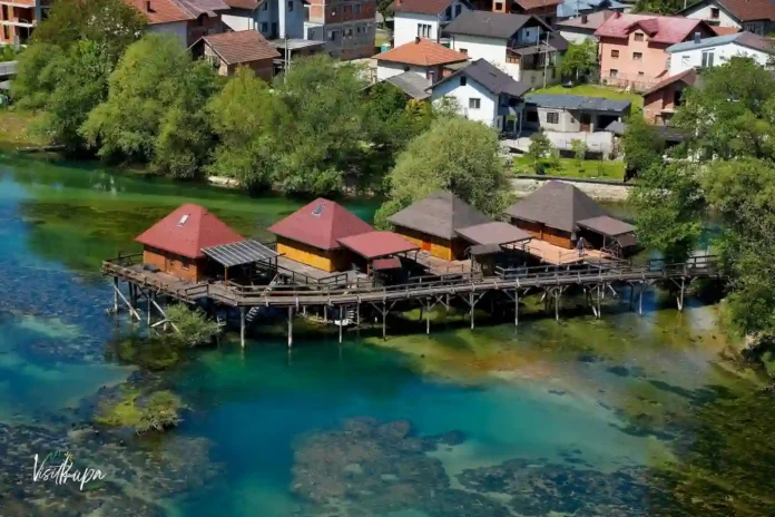 Krušnica rijeka s drvenim kućama na obali, prirodna ljepota i mirna atmosfera.