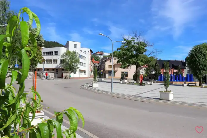 Prazan trg u Bosanskoj Krupi pod plavim nebom i zelenim drvećem.