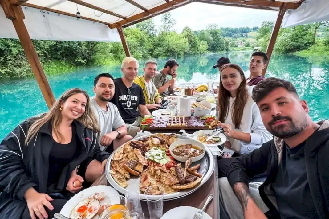 Grupa ljudi uživa u obroku na brodu pored Krušnice, okruženi prirodom.