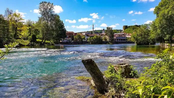 Krušnica rijeka u Bosanskoj Krupi s zelenim obalama i plavim nebom.