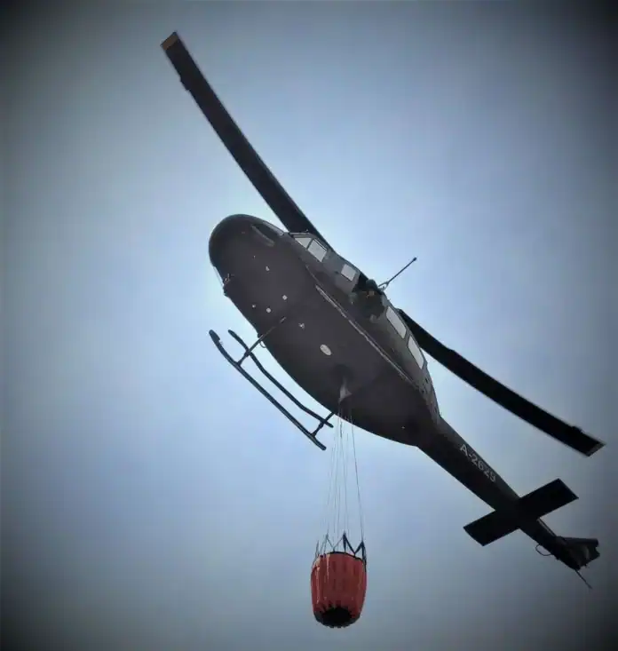 Helikopter za gašenje požara s crvenim teretom u zraku.