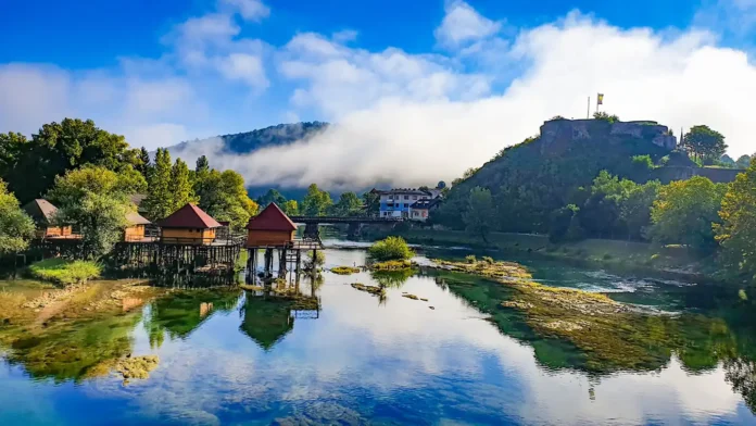 Prekrasan pogled na rijeku i branu u Bosanskoj Krupi s planinama u pozadini.