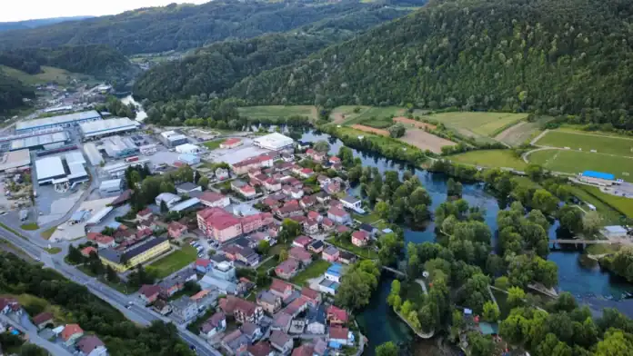 Pogled na Bosansku Krupu s rijekom i zelenim brdima u pozadini.