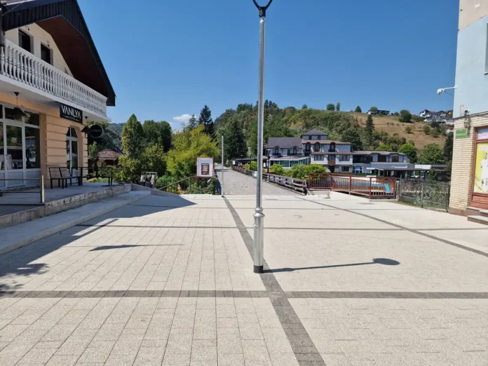 Prazan trg u Bosanskoj Krupi s lampom i zgradama u pozadini.